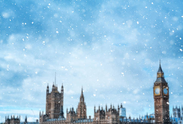 Snowing In London Christmas spirit in London. Defocused Big Ben and Houses of Parliament with falling snowflakes in the foreground. winter wonderland london stock pictures, royalty-free photos & images