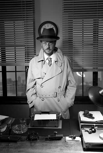 Attractive detective standing next to his desk, 1950s style office.