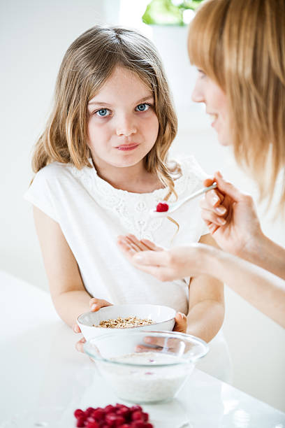istock Mother feeding daughter with muesli and raspberries 490052772