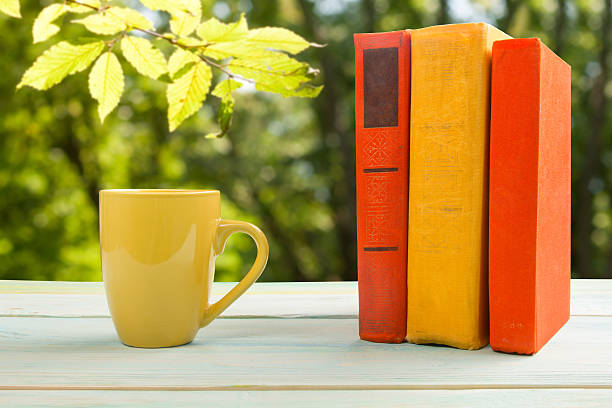 istock Stack of colorful books and cup on wooden table 490057508