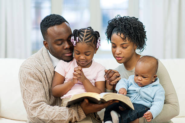 Black family bible studying African American Family studying bible together black father son reading stock pictures, royalty-free photos & images