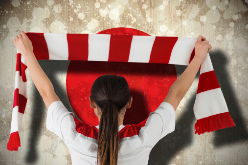 Composite image of football fan waving red and white scarf against japan flag