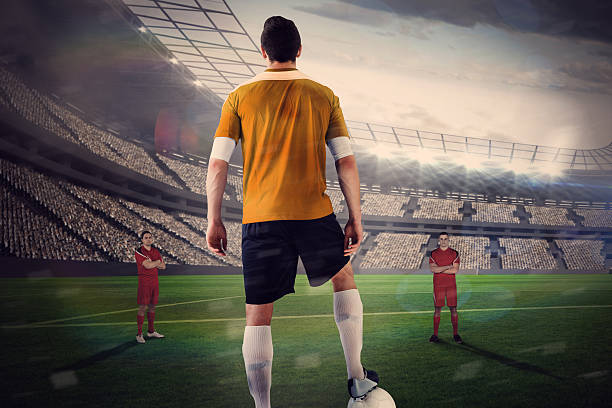 istock Football player in yellow with ball facing opposition 490066629