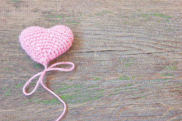 istock pink knitted heart on a cracked old wooden texture 490066739