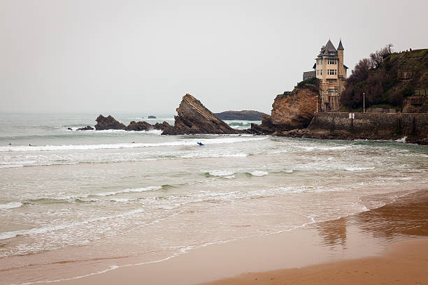 Surfers carrying their boards and walking on the Cote des Basques beach in Biarritz