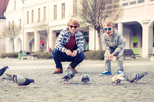 istock Two brothers feed a doves on the old city square 490070278