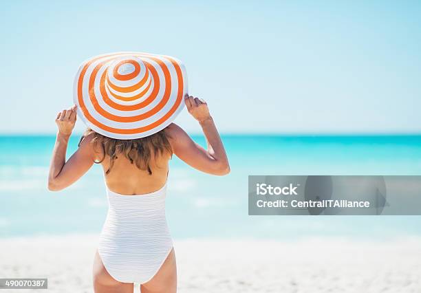 Young Woman In Hat Standing On Beach Rear View Stock Photo - Download Image Now - Women, Beach, Hat