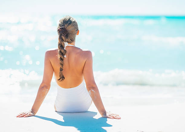 Young woman sitting at seaside. rear view