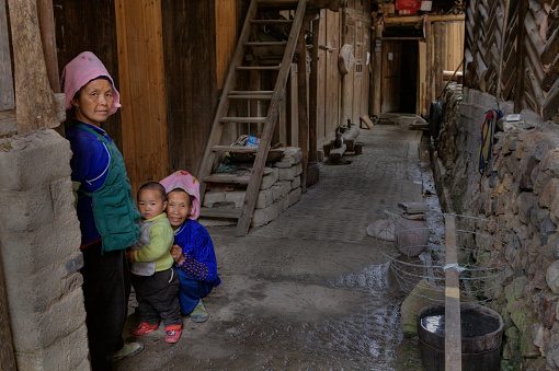 Xijiang miao village, Guizhou Province, China - April 17, 2010: Rural Wooden Peasant Farmer House Yard, Two mature Asian woman and a child, a little boy, about 2 years old.
