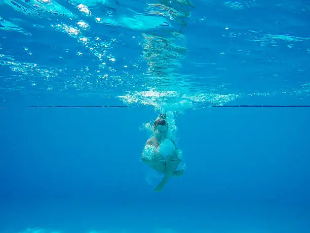 Underwater shot of boy jumping into pool 