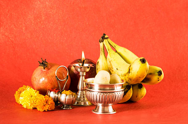 hindu puja elements, diya, haldi kumkum,apple, pomegranate and banana as offering to god and indian sweet pedha in silver bowl, isolated on red background