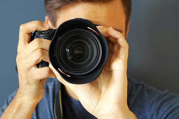 istock Young Photographer Shooting With A Professional Camera With Grey Background 490083986