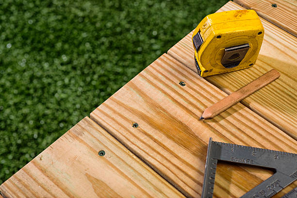 Carpenter's Pencil, square and tape sitting on a wood deck Carpenter's pencil, an aluminum speed square and yellow measureing tape sitting on a newly contructed outdoor deck, built with 2X6 Pressure Treated, with grass in the background Southern Yellow Pine, this dimensional lumber typically used for residential decking and other outdoor projects. yard measurement stock pictures, royalty-free photos & images