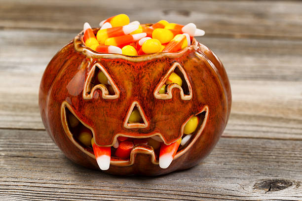 istock Spooky fanged pumpkin filled with candy corn on rustic wood 490084954