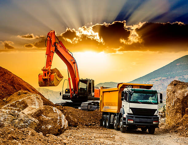 Moving Mountains at sunset Industrial truck loader excavator moving earth and loading into a dumper truck at sunset. construction truck bulldozer wheel stock pictures, royalty-free photos & images