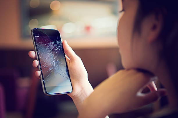 Broken mobile phone Young girl is watching her broken mobile phone after falling down. breaking stock pictures, royalty-free photos & images