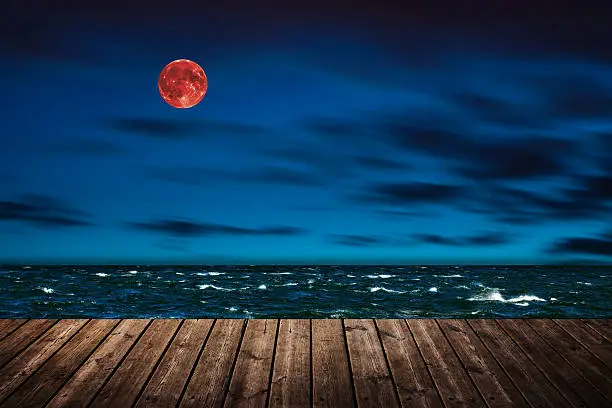 Red full moon in red color also called bloodmoon on the background sea.