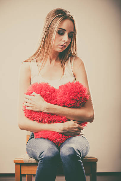istock Sad unhappy woman holding red heart pillow 490111422