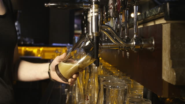 pouring a pint of guinness from beer tap in pub