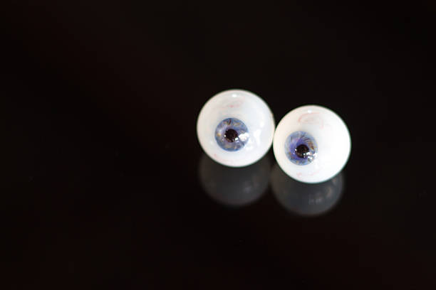 vetro (con occhi verso blu iris), su sfondo nero riflettente - occhio di vetro foto e immagini stock