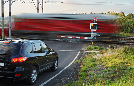 Speeding motion blur red train passing through a railway crossing