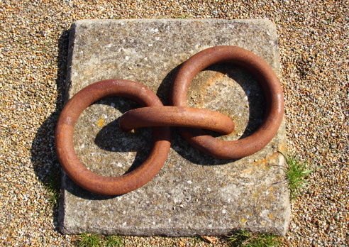 Rusty metal bollard rings mounted to concrete block isolated