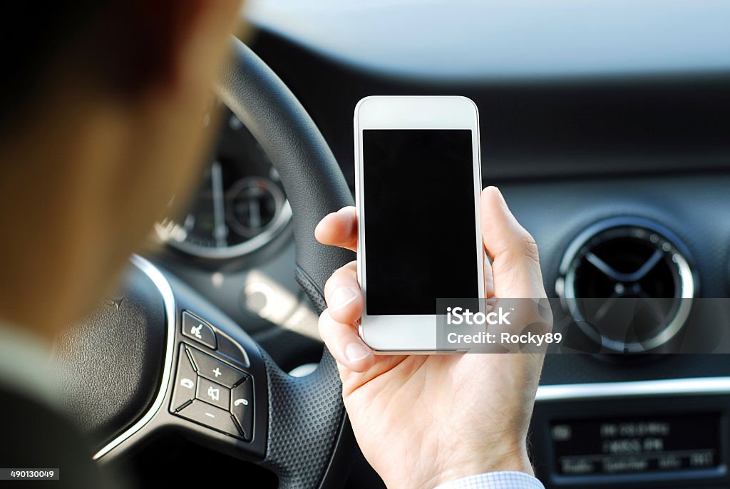 Businessman texting while driving a car Businessman texting on his smart phone while driving a car Adult Stock Photo