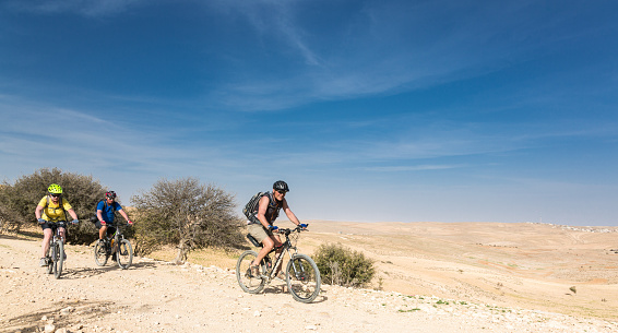 A group of mountainbikers is riding on a gravel road in the Jordan Highlands.
