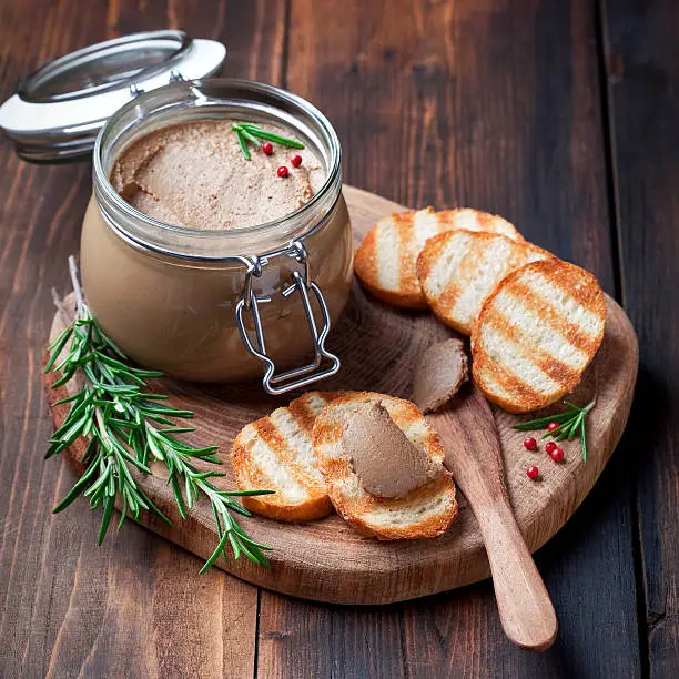 Chicken liver pate in jar and on bread, selective focus