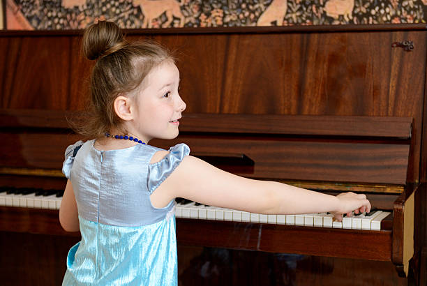 Little girl playing piano Blue weared little girl playing piano, girl playing piano stock pictures, royalty-free photos & images
