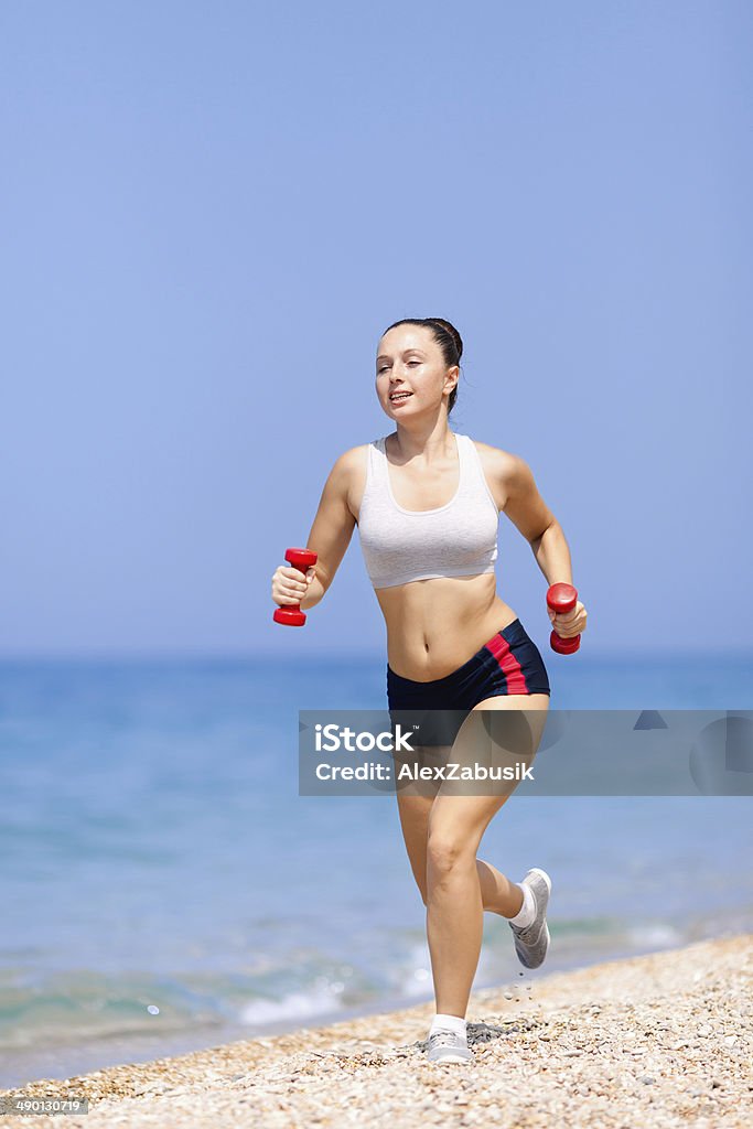 Girl at the sea Girl at the sea. Young woman in summer sportwear running along pebble beach. 20-24 Years Stock Photo