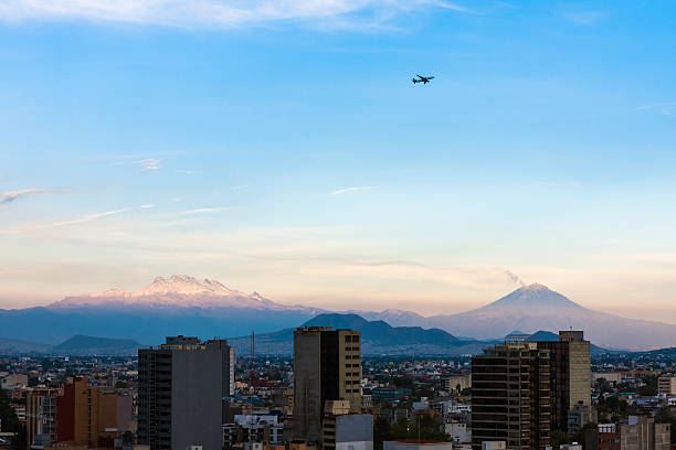 Mexico City volcanoes Mexico city at dusk with volcanoes in background, Popo and Izta on a clear day, an airplane is passing by popocatepetl volcano photos stock pictures, royalty-free photos & images