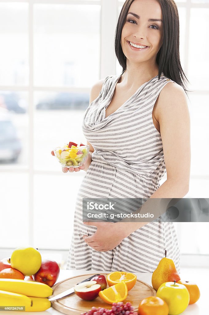 Only fresh and healthy food for my baby. Cropped image of pregnant woman holding a plate wirh fruit salad Adult Stock Photo