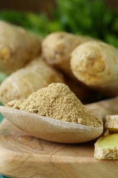 istock ground ginger in a wooden spoon, fresh root in the background 490134975