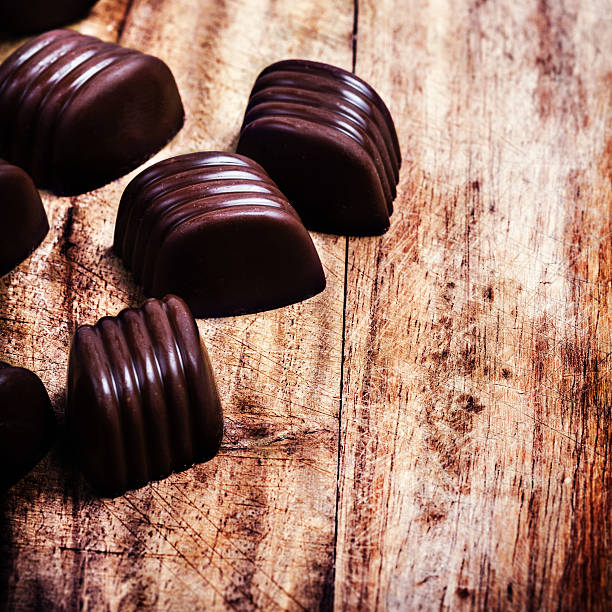 istock Chocolate candies on old wooden textured background close up. 490136323