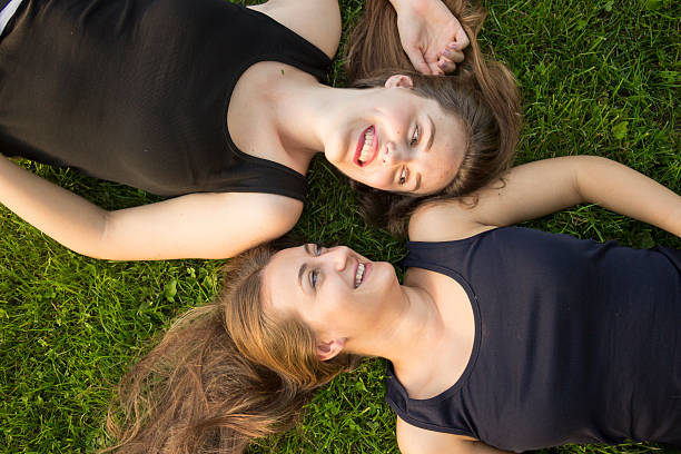 istock Two girls, making funny faces. Laying in green grass 490136452