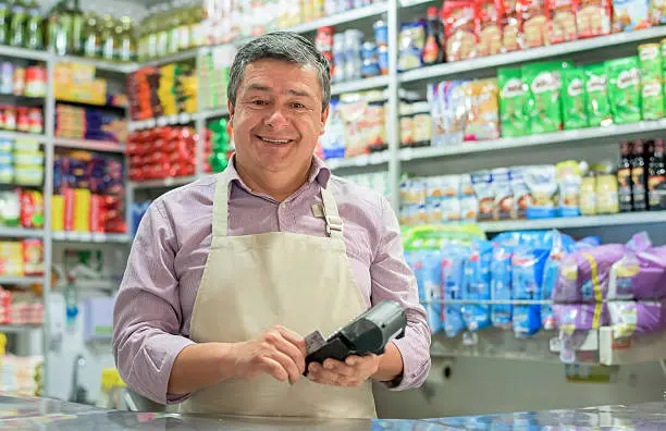 Business owner at a local shop holding a credit card reader - using technology concepts