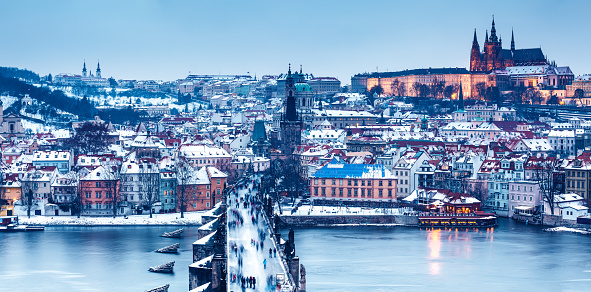 Panoramic winter view over the famous Charles Bridge in Prague, Czech Republic, to the snow covered skyline of the old town