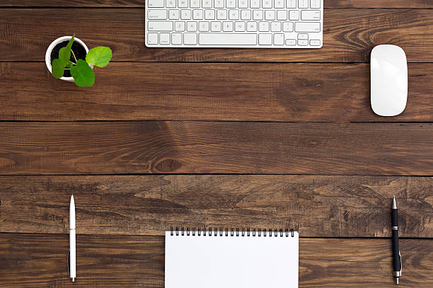 istock Brown Wooden Desk with Stationery Electronics and Flora 490185962