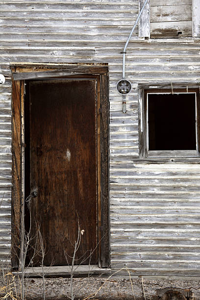 Pictures of abandoned, ruined barns in central Alberta depict a haunting yet compelling scene of decay. The barns, with their broken and misshapen walls, stand as weathered relics of the past, their once-sturdy structures now leaning and partially collapsed. Shattered windows and crumbling woodwork add to the sense of abandonment, with the desolate, overgrown surroundings further emphasizing the barns' long-forgotten state.