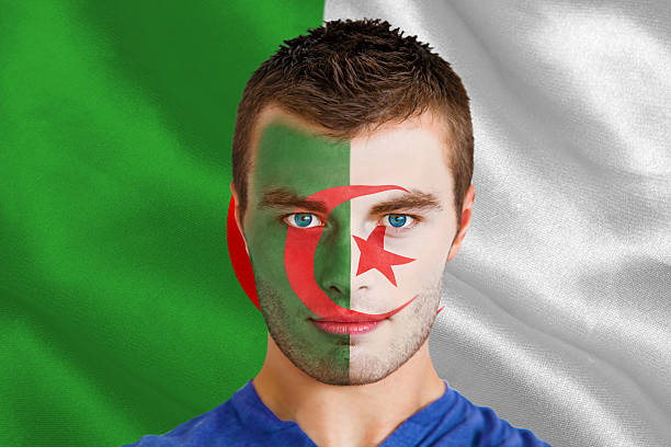 Serious young algeria fan with facepaint Composite image of serious young algeria fan with facepaint against algerian flag algeria soccer stock pictures, royalty-free photos & images