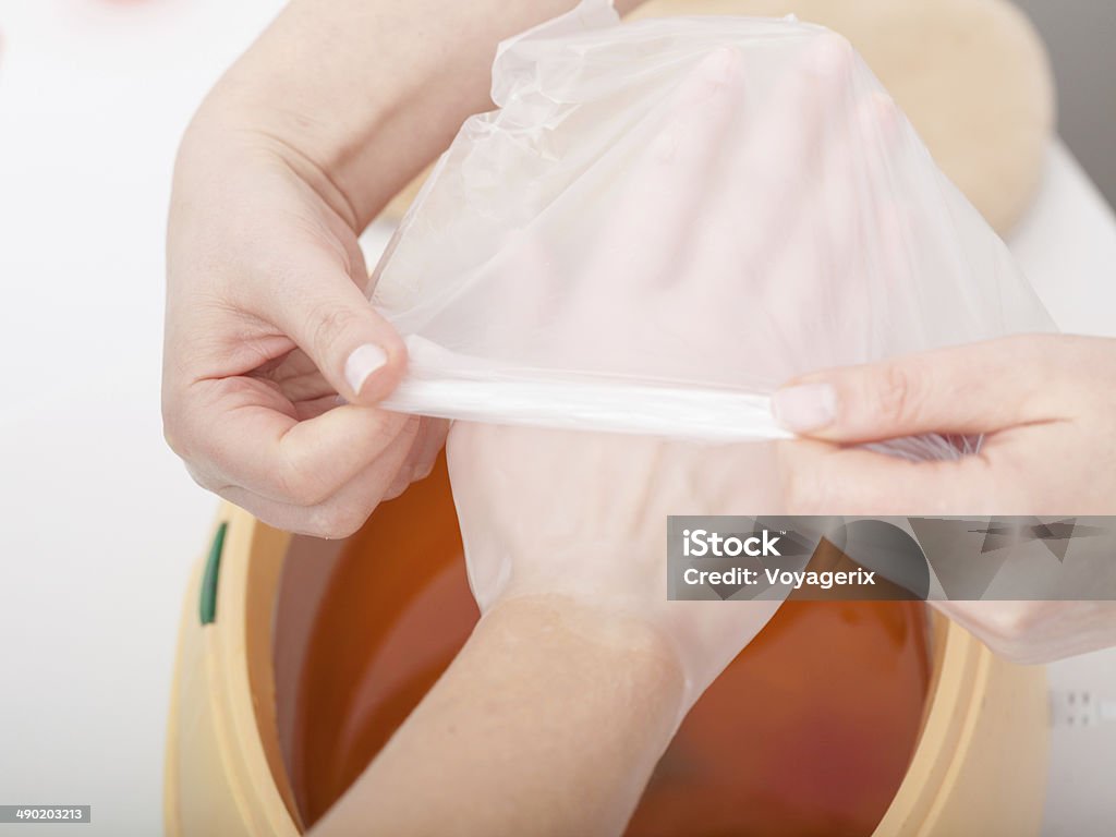 Female hand and paraffin wax bowl. Woman in beauty salon Female hand and orange paraffin wax in bowl. Manicure and skincare. Woman girl in beauty spa salon. Adult Stock Photo