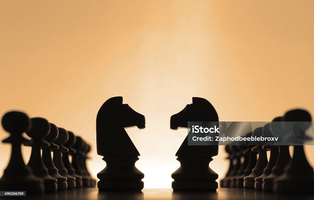 Chess pieces Silhouettes of knights chess pieces surrounded by pawns Confrontation Stock Photo