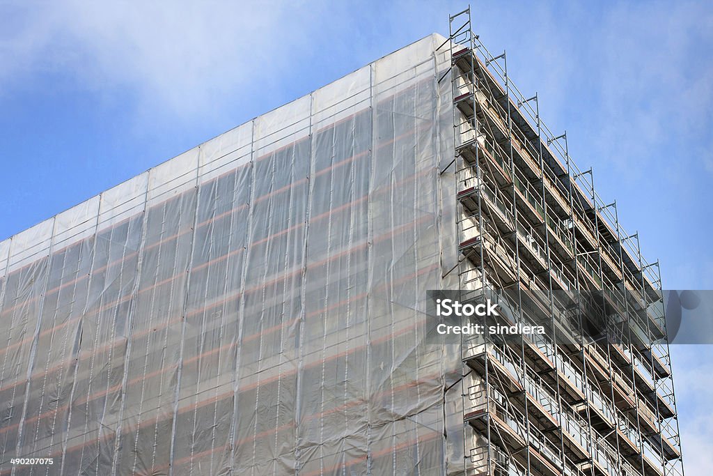 Staircase and scaffolding on a construction site,covered with mesh. Staircase and scaffolding on a construction site,covered with mesh on sky background. Aluminum Stock Photo