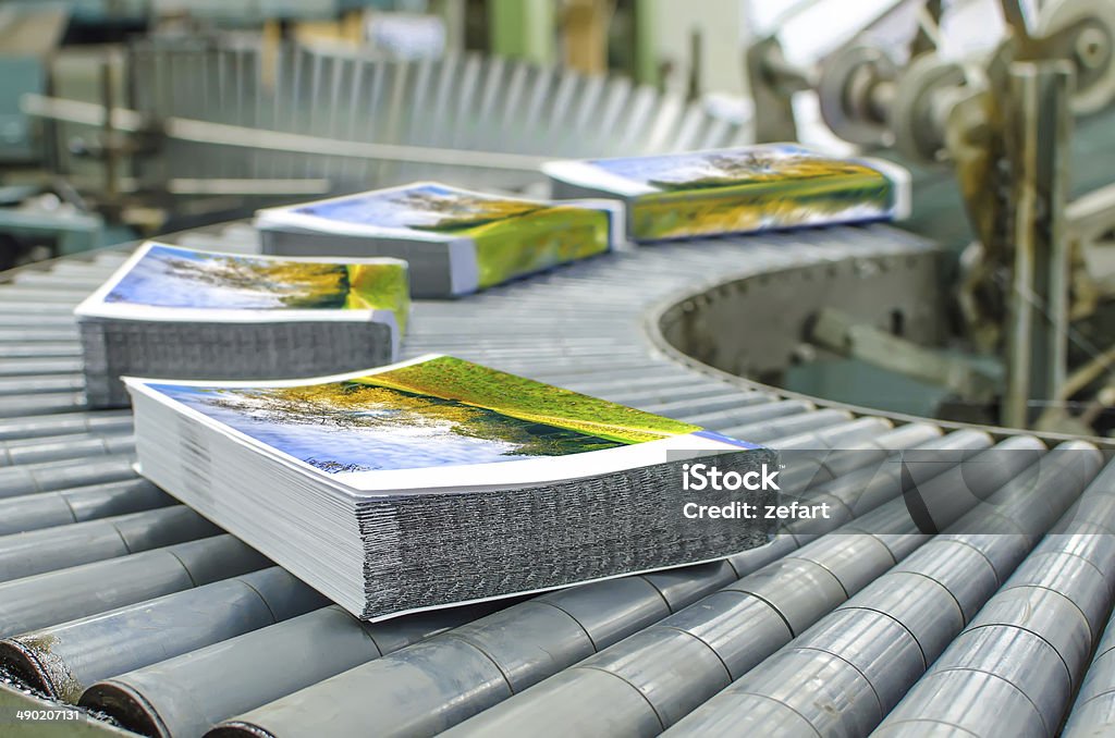 Book, magazine, catalog production line into press plant house. Binding cover and assembling with the spline. Printing Press Stock Photo