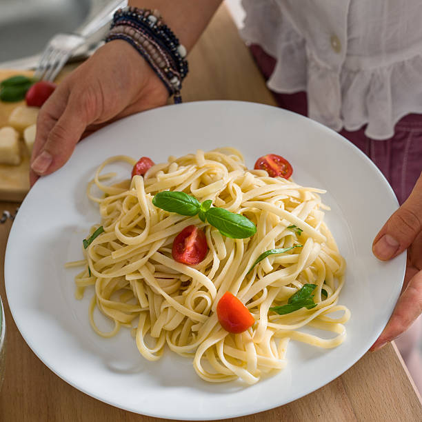 istock Woman holding a plate with fresh spaghetti pasta 490211978