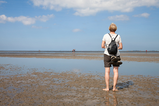 Germany, Lower Saxony, Low tide, woman standing on water's edge