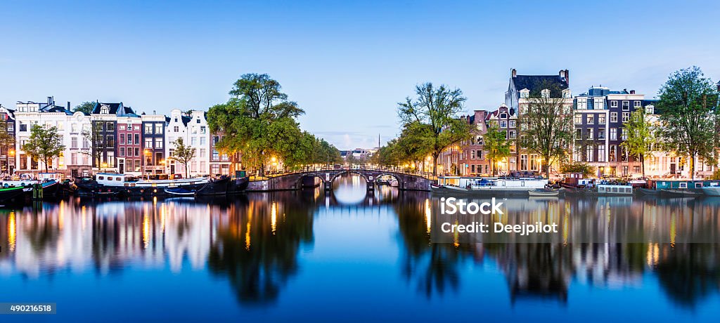 Bridges and Canals of Amsterdam Illuminated at Sunset Holland Bridge and canal houses in Amsterdam at twilight, Holland. Amsterdam Stock Photo