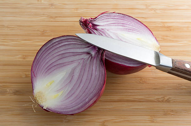 istock Large red onion halved on cutting board with knife 490218868