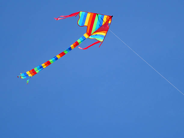istock Image of kite with rainbow stripes flying against blue sky 490223264